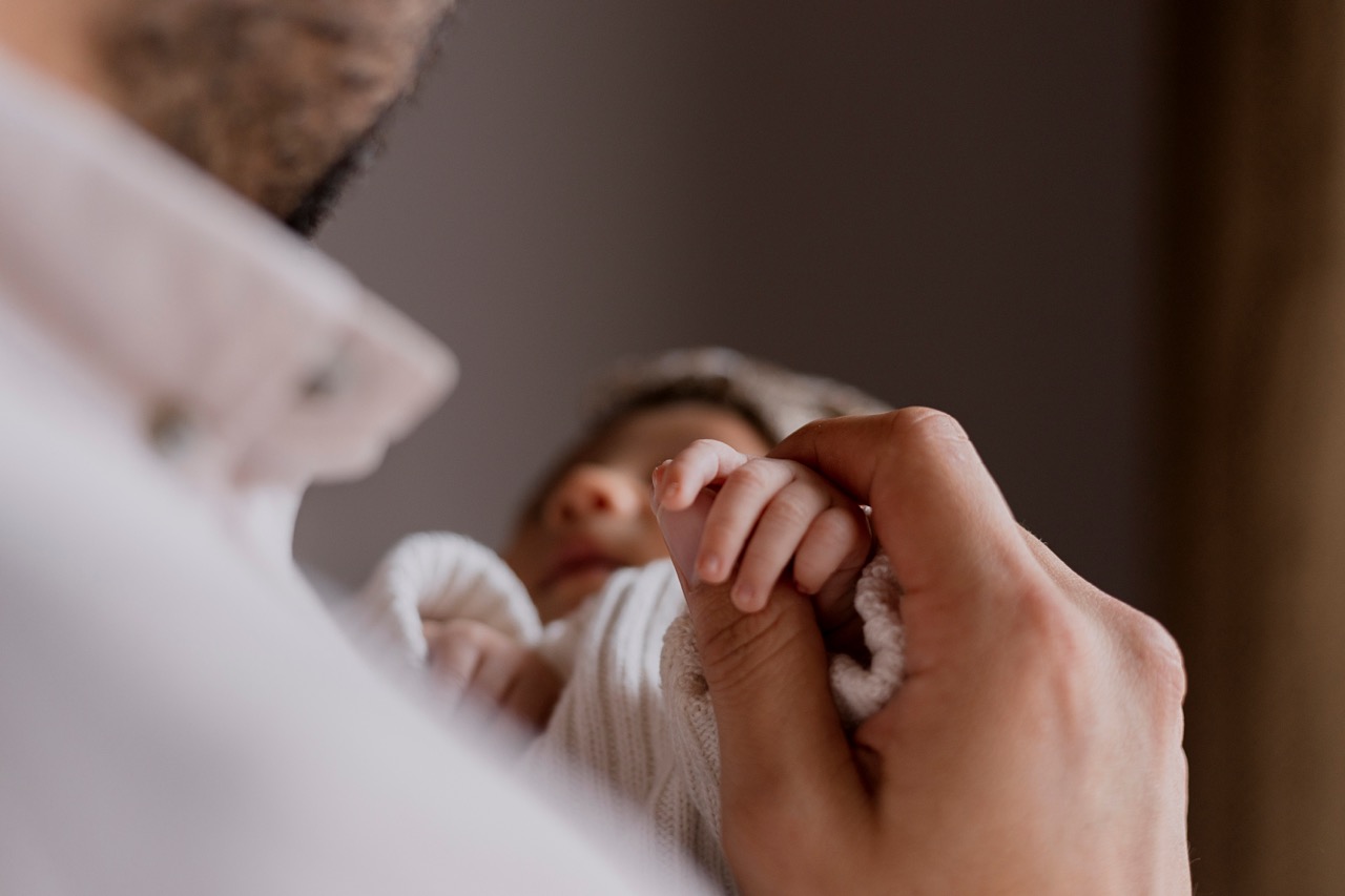 Newborn gripping father's finger